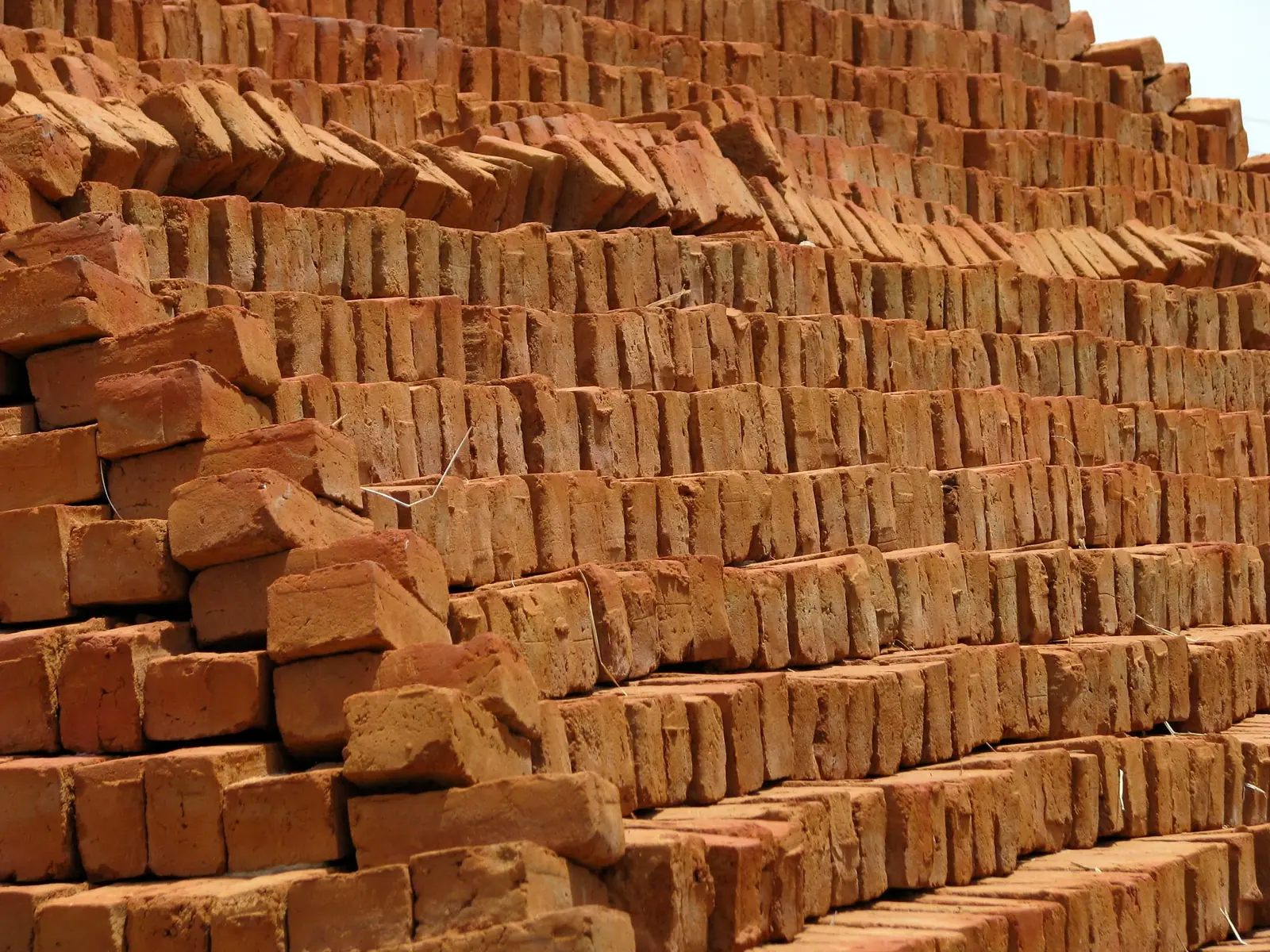 Close-up of stacked, fired red bricks showing their colour and edges