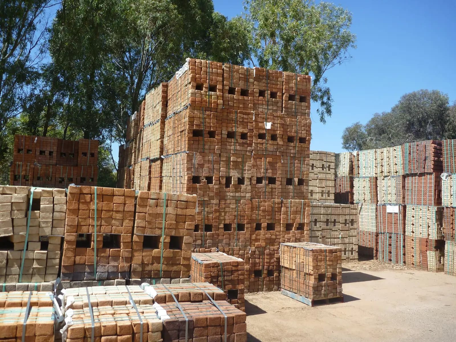Bundled red bricks stacked in tall blocks on a yard, ready for loading and delivery